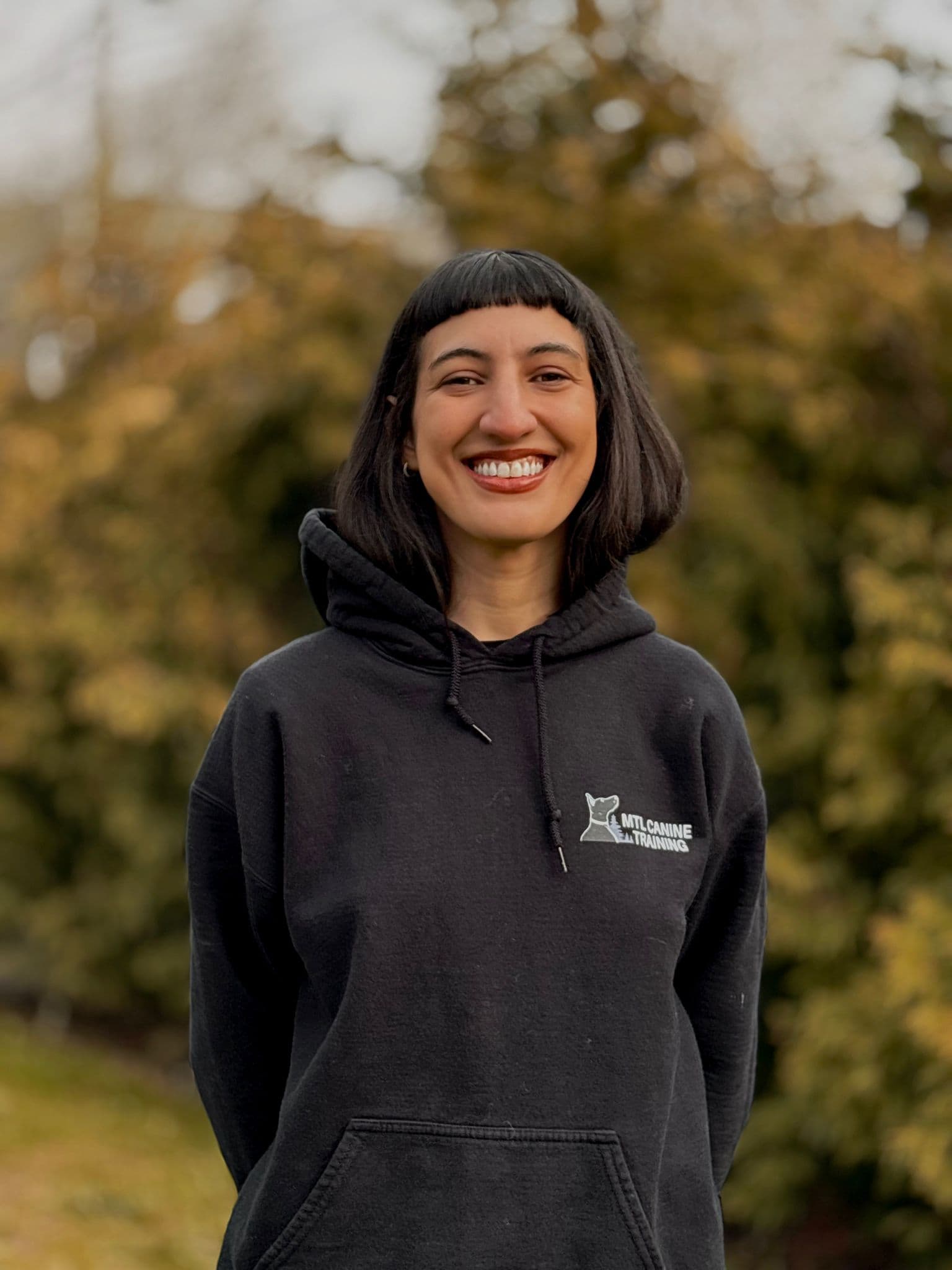 Portrait of Mia M smiling in a Montreal Canine Training hoodie outdoors